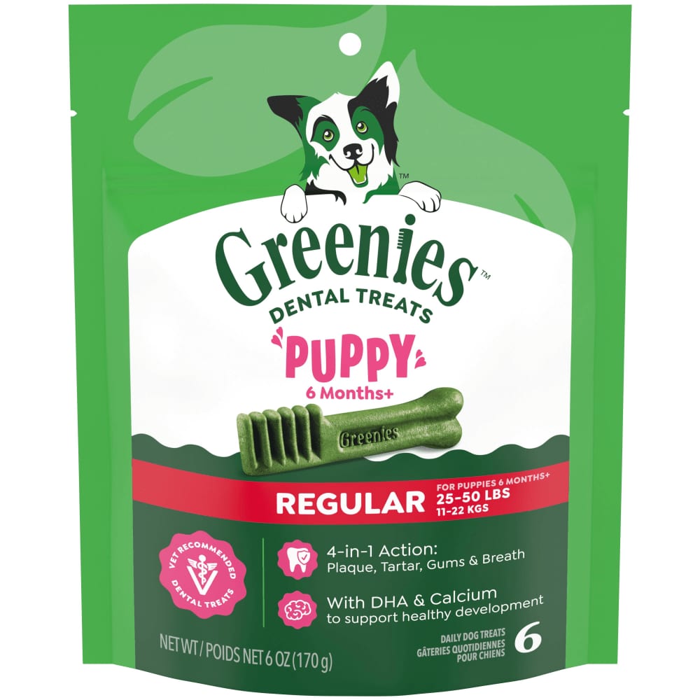 A Greenies Original dental chew held next to a dog's open mouth